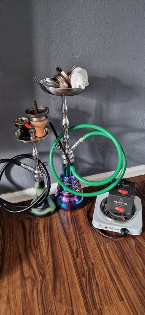 Shisha mit Glasbowl, Schlauch und Kohle auf Holzoberfläche.