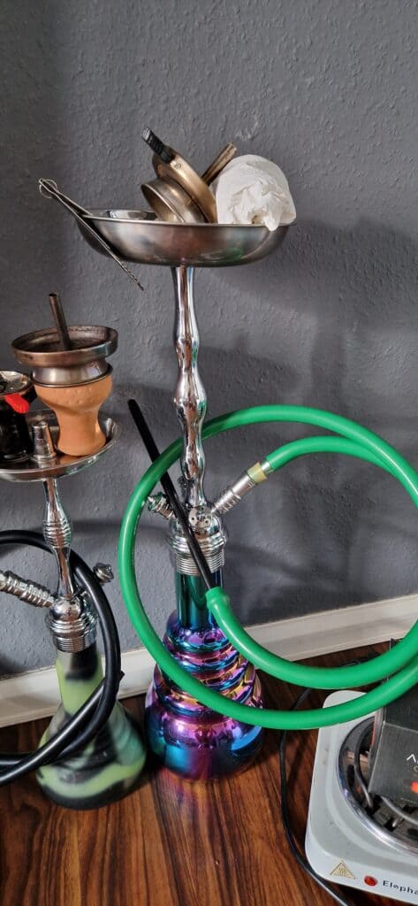 Verschiedene Shisha-Teile, Glasbowl, Schlauch und Tabakkopf.