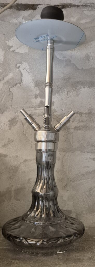 Stilvolle Shisha mit Metall- und Glasbestandteilen, auf Betonwand montiert.