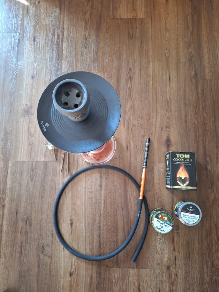 Shisha Zubehör mit Glasbowl, Schlauch, Zigarettenanzünder und Tabak.