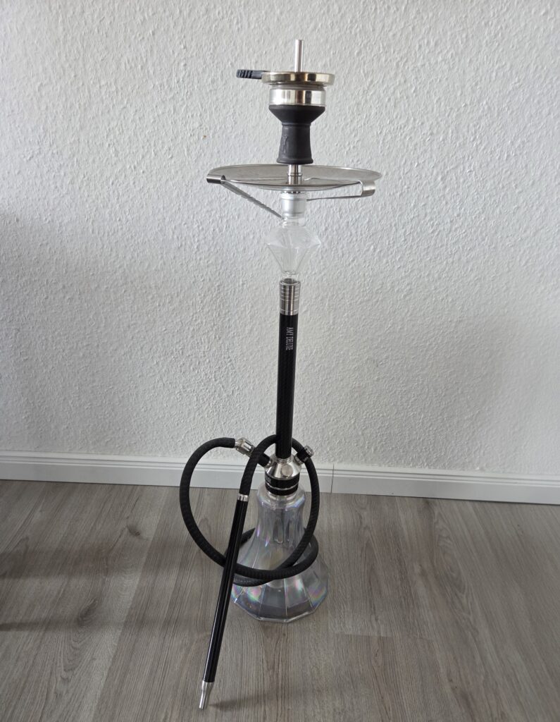 Shisha mit Glasbowl, Schlauch und Kopf, auf Boden stehend.