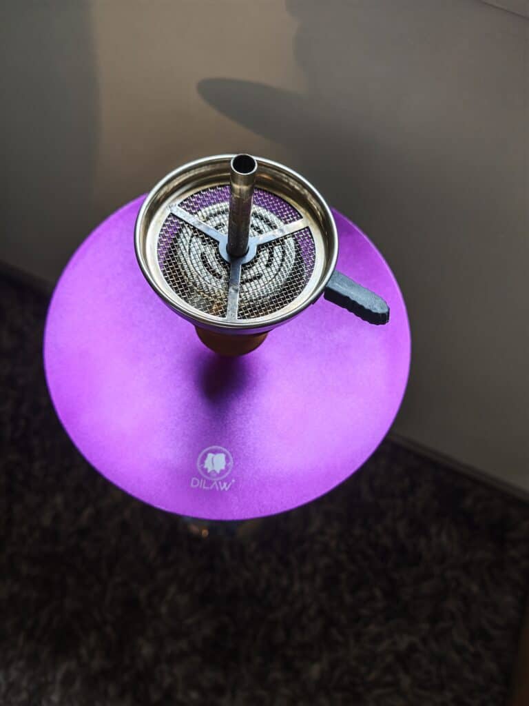 Shisha mit Metall- und Glasbowl auf pinker Oberfläche.