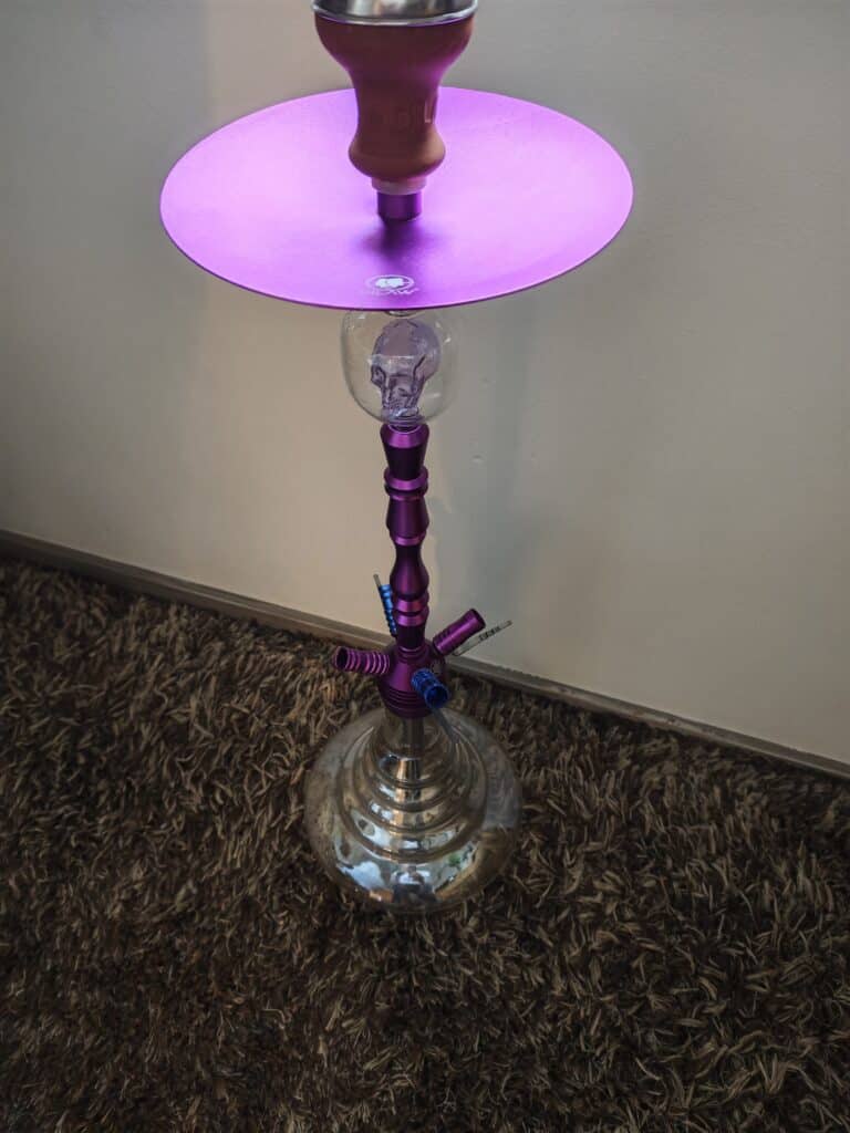 Bunter Shisha-Kopf mit Glasbowl auf einem Tisch.