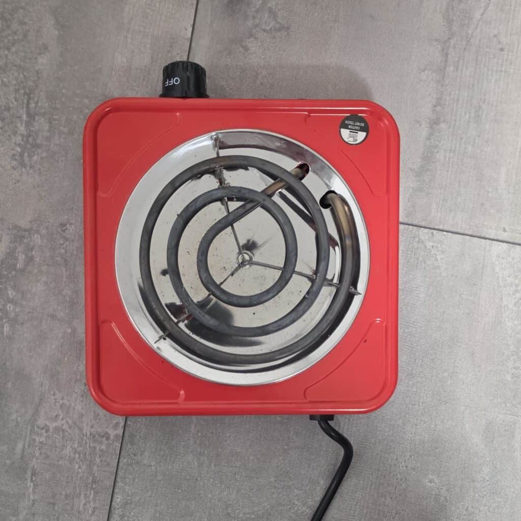 Rote elektrische Kochplatte mit Spirale und Kabel.
