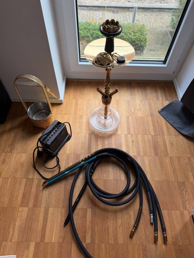 Shisha Bowl mit Schlauch und Zubehör vor Fenster.