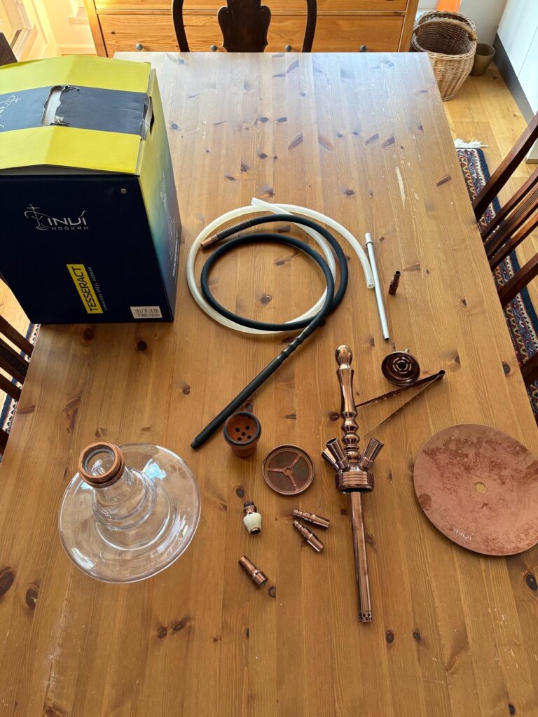 Verschiedene Shisha-Teile und Zubehör auf Holztisch.