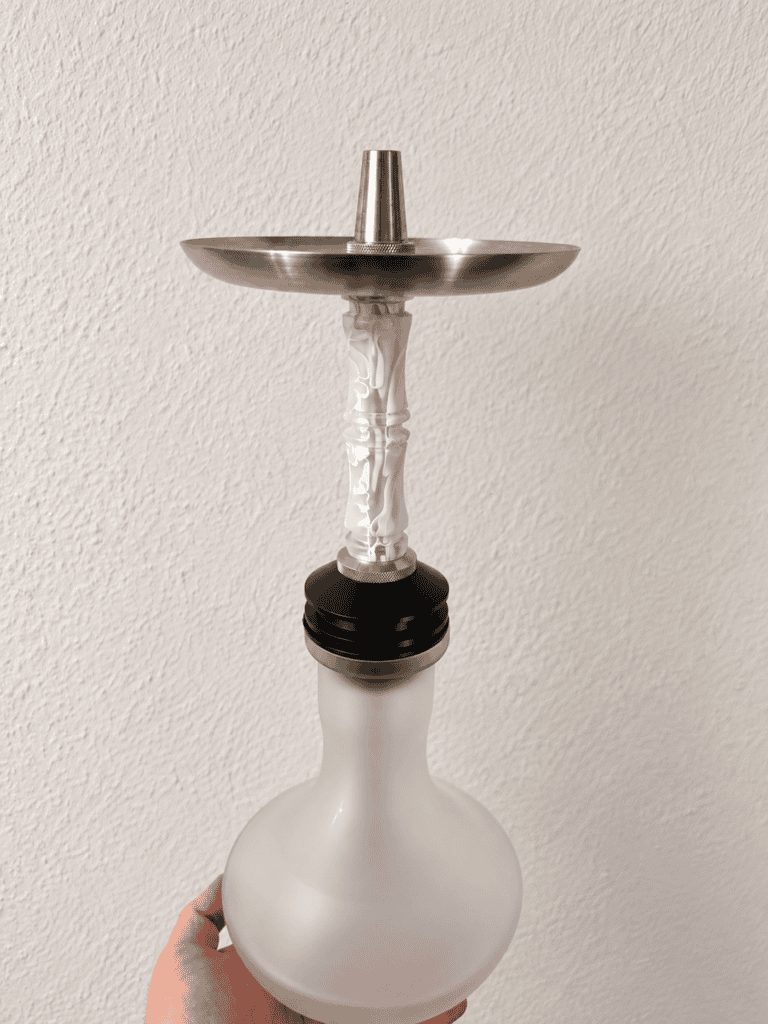 Moderne Shisha mit Metall- und Glasbowl, handgehalten vor neutraler Wand.
