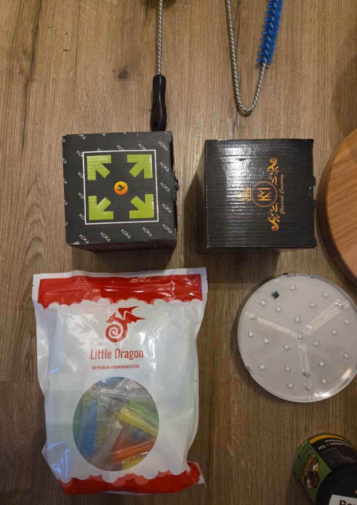 Verschiedene Shisha Zubehörteile, inklusive Glasbowl, Zigarettenanzünder und Reinigungsbürste.