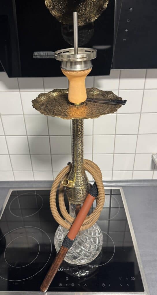 Alte Shisha mit Glasbowl und Zubehör auf Herdplatte.