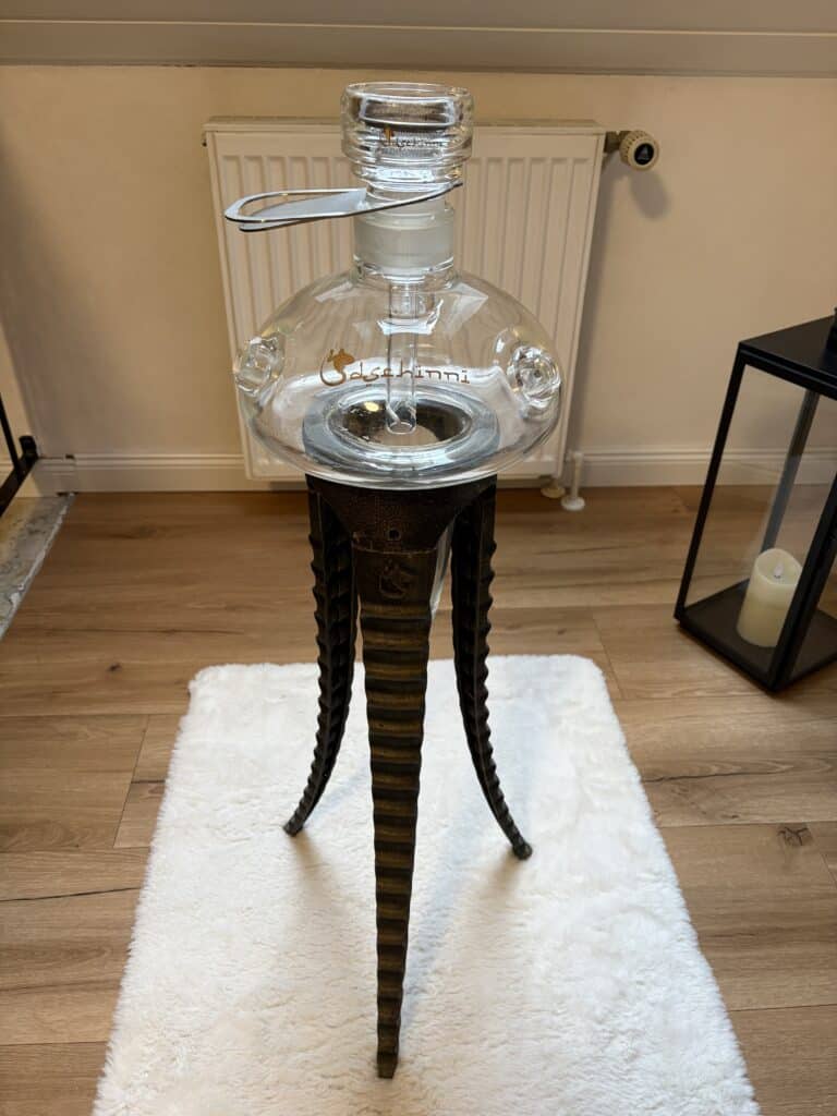 Klarer Glasbowl für Shisha auf einem schwarzen Holzständer.