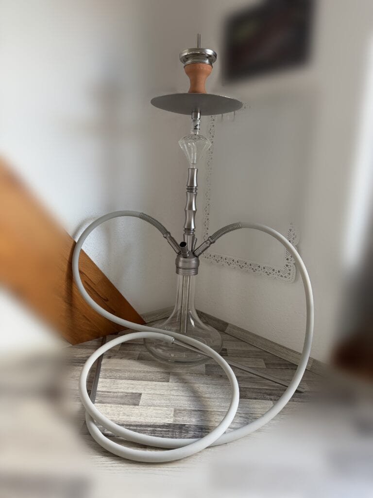 Shisha-Kopf mit Glasbowl und Schlauch, auf Boden stehend.