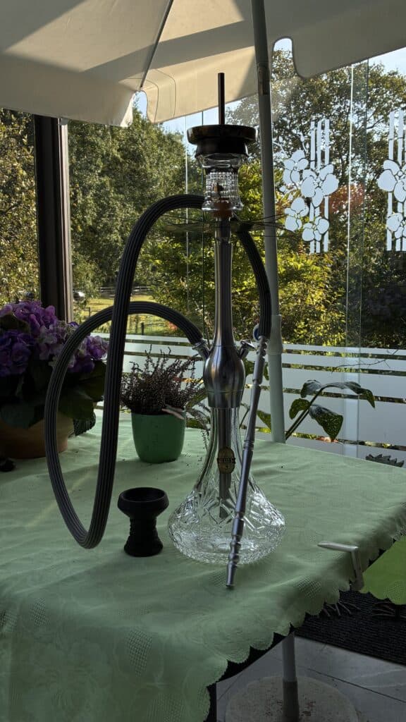 Moderne Shisha mit Glasbowl und Silikonschlauch auf Tisch.