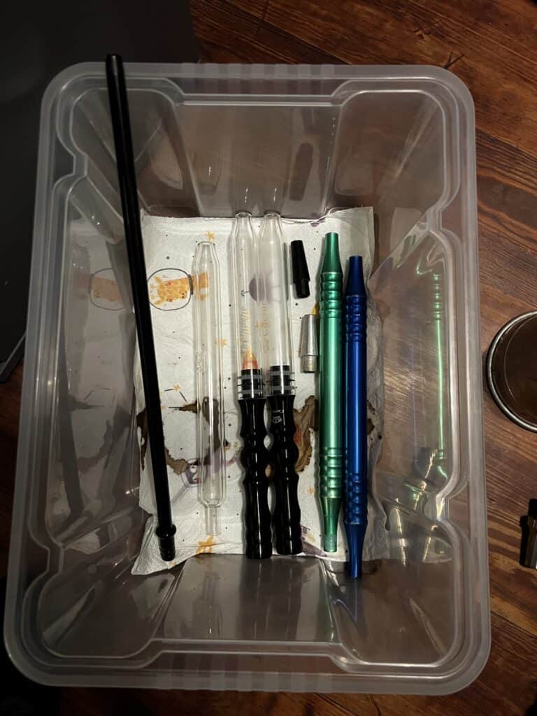 Verschiedene Shisha-Zubehörteile in einem transparenten Behälter.