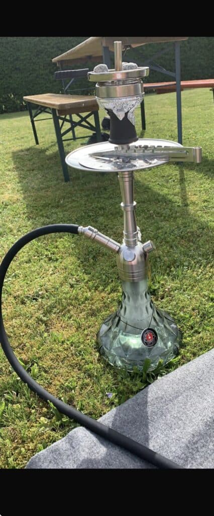 Shisha im Garten mit Edelstahlkopf und Glasbowl auf Rasen.