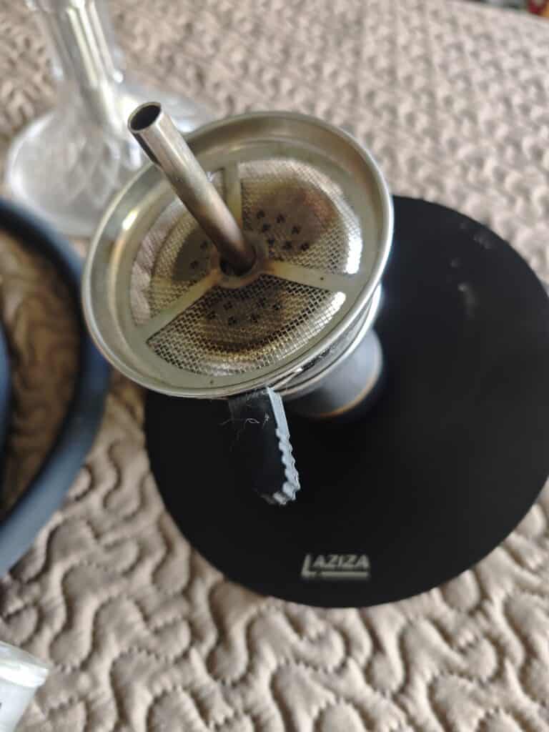 Shisha Glasbowl mit Metallrohr und Sieb, auf schwarzem Standfuß.
