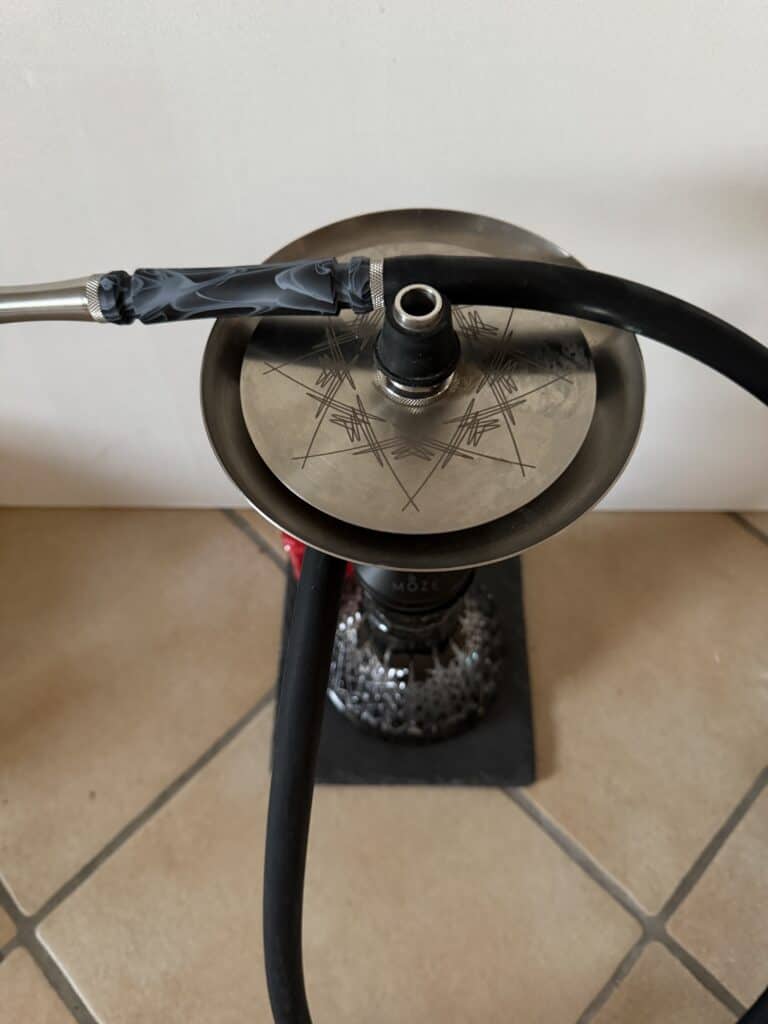 Shisha mit Glasbowl, Schlauch und Kopf auf Boden.