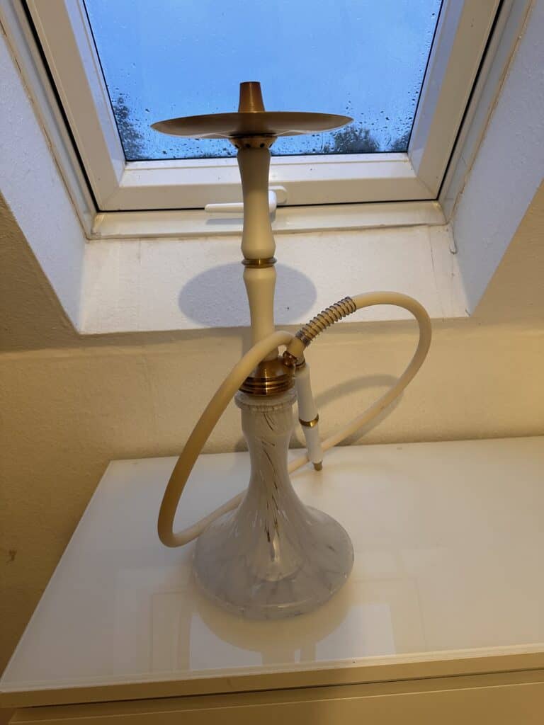 Shisha-Kopf mit Glasbowl auf Fensterbank, Blick nach draußen.