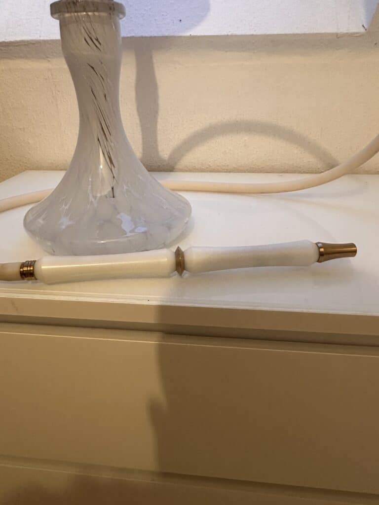 Shisha Glasbowl mit Rauchsäule auf weißem Tisch.