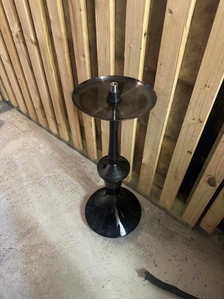Schwarzer Shisha-Tabakständer mit Glasbowl auf Boden.
