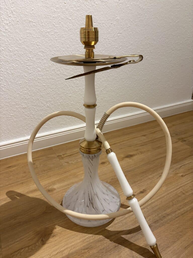 Shisha-Kopf mit Gold-Details und Schlauch auf Holzboden.