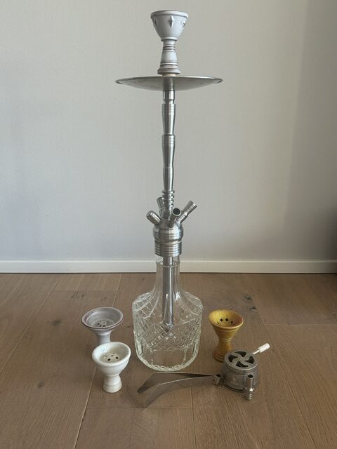 Verschiedene Shisha-Teile und Glasbowl auf Holzboden.