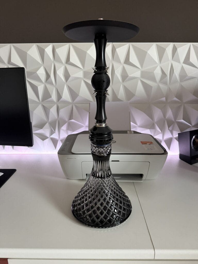 Schwarze Glasbowl für Shisha auf Tisch mit moderner Wanddekoration.