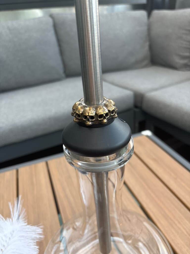 Shisha-Glasbowl mit Metallrohr auf Holztisch.