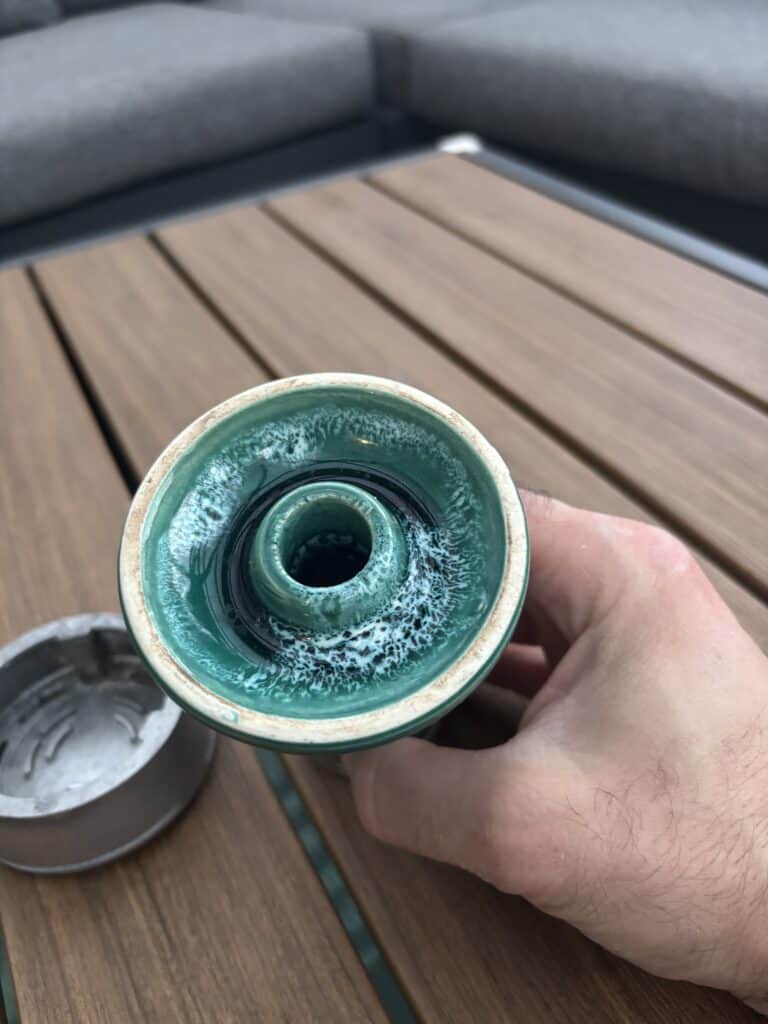 Nahaufnahme einer grünen Shisha-Glasbowl mit Wasser und Rauch.
