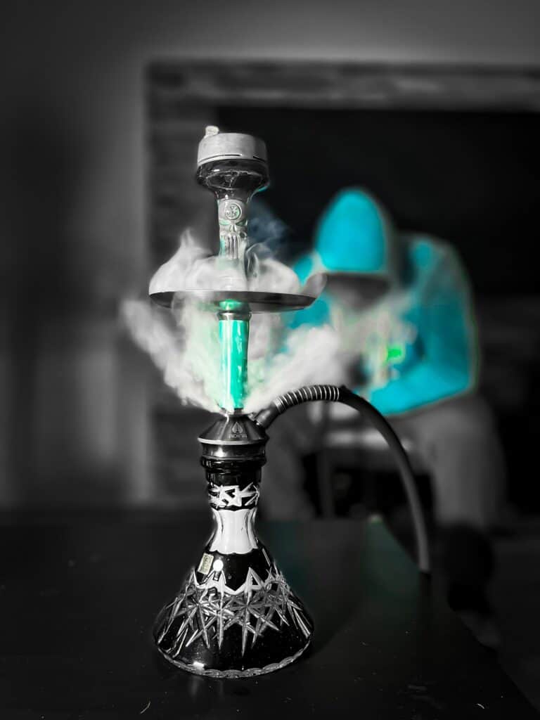 Shisha mit Glasbowl, Rauchentwicklung, dunkler Hintergrund.