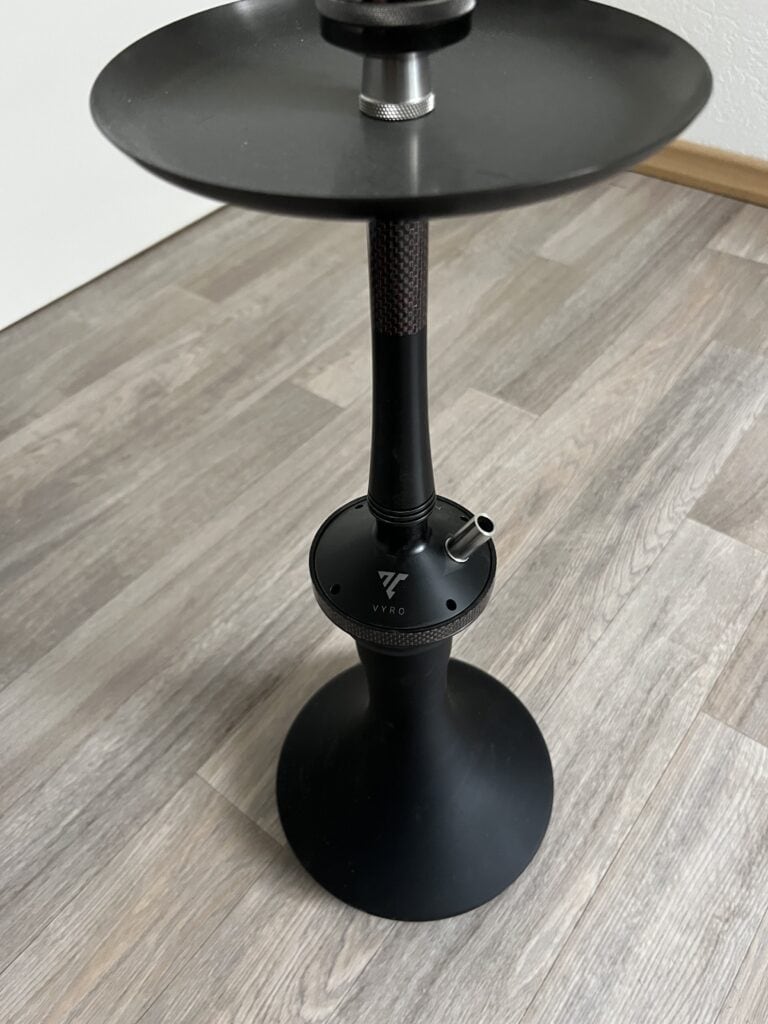 Schwarze Shisha-Halterung mit Ablagefläche auf Holzboden.