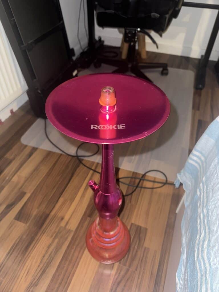 Bunte Shisha mit pinker Glasbowl auf Holzboden.