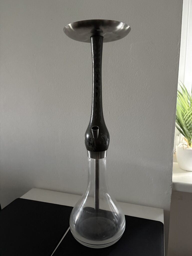 Schwarze Shisha-Glasbowl mit Metallaufsatz auf Tisch.