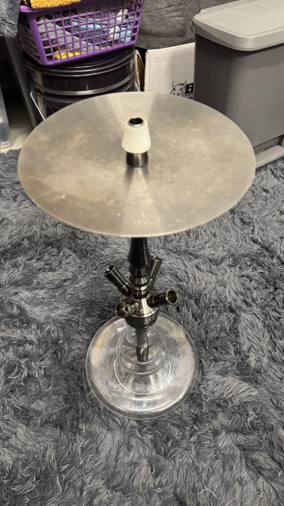 Shisha-Tabak mit Glasbowl und Metallaufsatz auf Teppichboden.