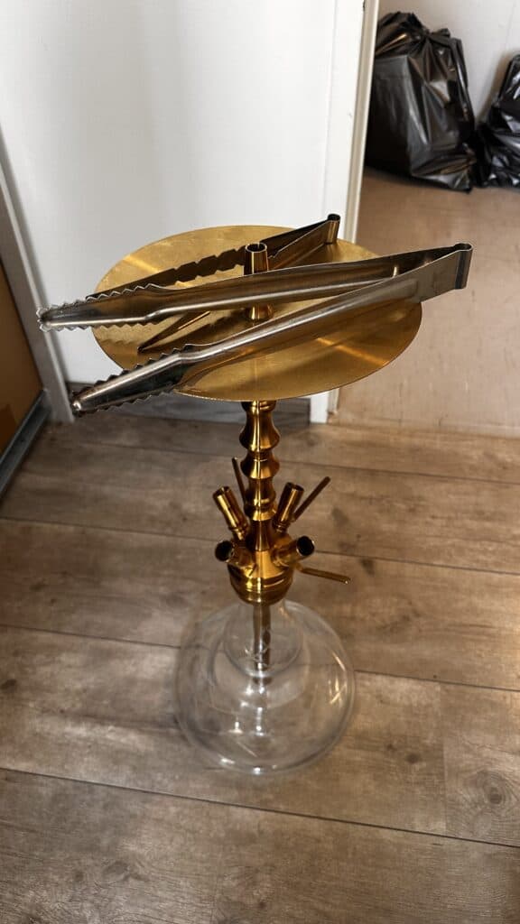 Shisha-Tabakständer mit goldener Glasbowl und Metallzubehör.