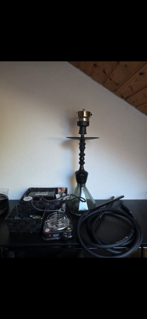 Shisha-Zubehör mit Glasbowl, Schlauch und Kohlezange.