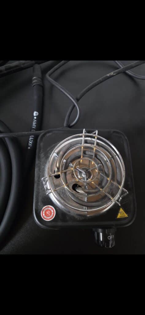 Elektrischer Heizstab mit Metallgitter und Kabelanschluss.