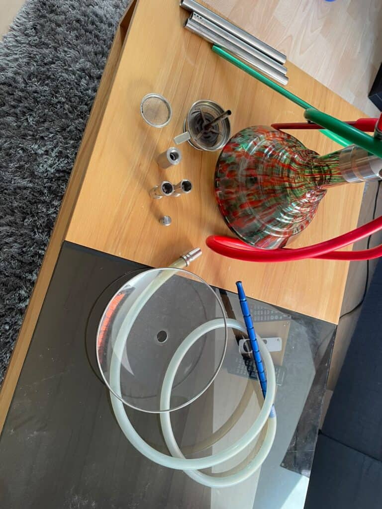 Verschiedene Shisha-Teile und Glasbowl auf Tisch.
