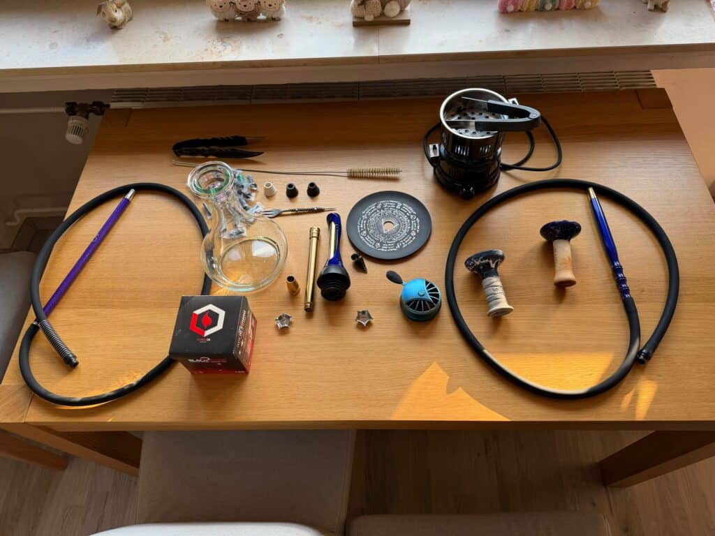 Verschiedene Shisha-Teile und Zubehör auf einem Tisch.