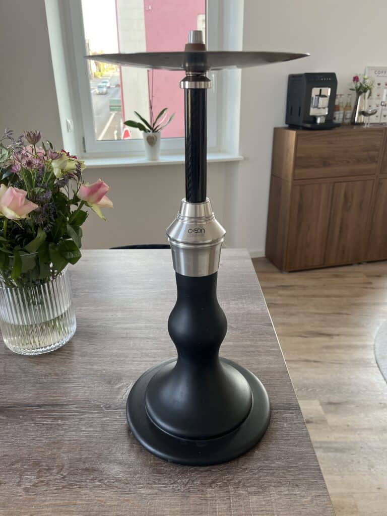 Schwarze Shisha mit Metall- und Glasbowl auf Holztisch.