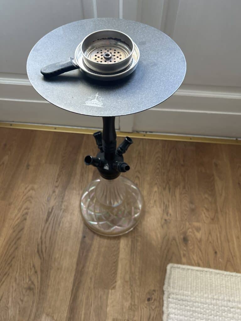 Shisha-Glasbowl auf einem schwarzen Tablett, auf einem Wasserpfeifenständer.