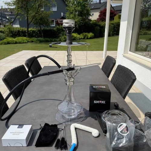 Rauchsäule und Shisha-Zubehör auf einem Tisch im Garten.