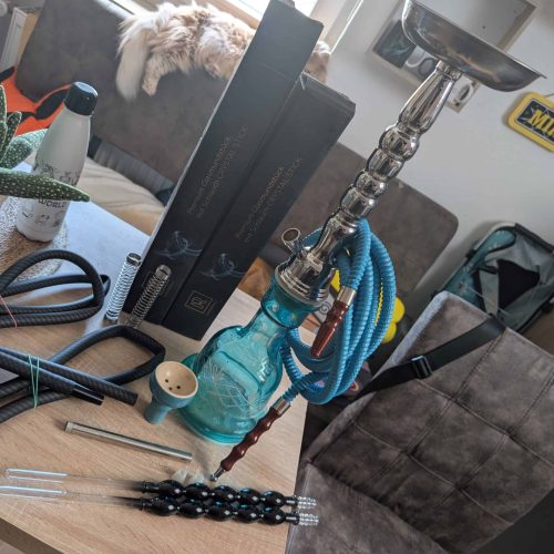Shisha mit Glasbowl und Zubehör auf Tisch.