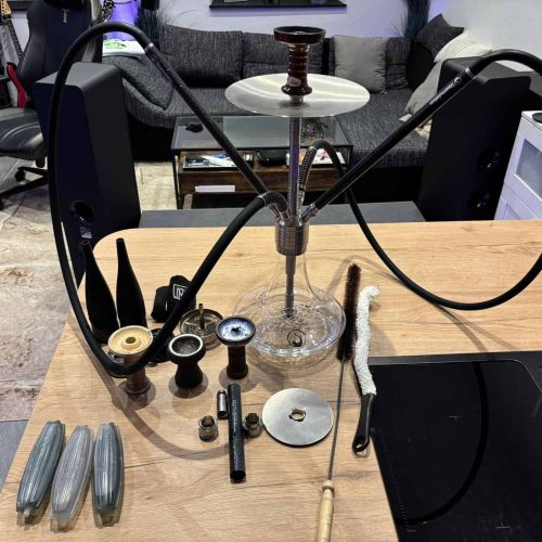 Rauchersäule mit Shisha-Set und Zubehör auf einem Tisch im Wohnzimmer.