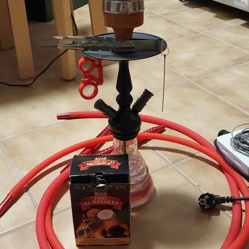Rauchsäule und Shisha-Set auf dem Boden, mit Schlauch und Zubehör.