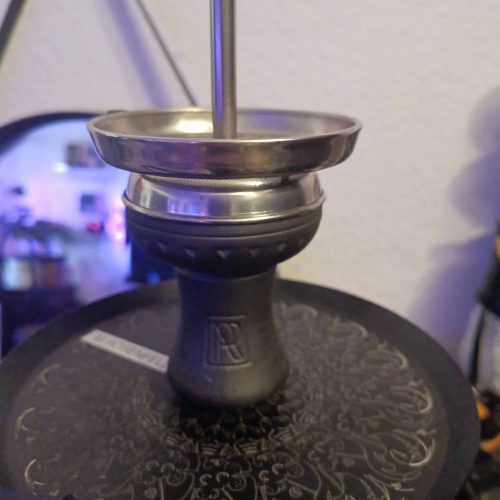 Shisha-Glasbowl mit Metallaufsatz und Stab, auf schwarzem Untergrund.