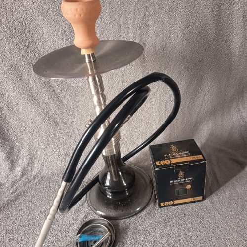 Shisha-Kopf mit Glasbowl, Schlauch und Zubehör auf Tisch.