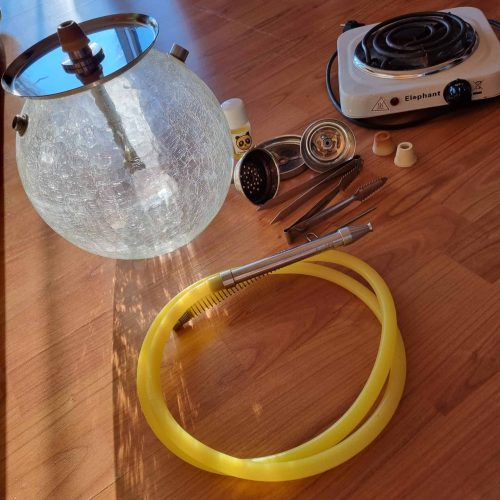 Glas-Shisha mit Heizgerät, Schlauch und Zubehör auf Holztisch.