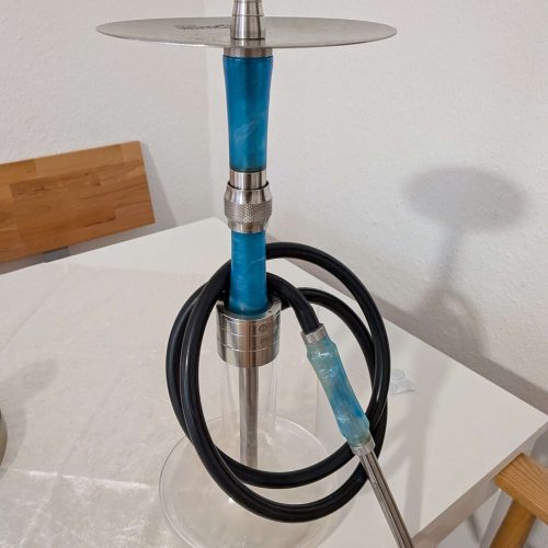 Moderne Shisha mit blauer Glasbasis und Metallaufsatz, auf Tisch stehend.