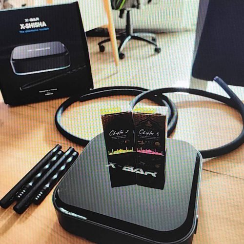 Dampfgerät für Shisha mit Zubehör, inklusive Kabel und Verpackung, auf einem Holztisch.