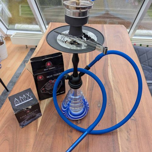 Rauchsäule mit Shisha, Tabak und Zubehör auf Holztisch, ideal für Raucher und Shisha-Liebhaber.